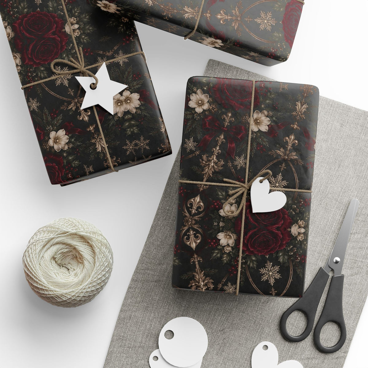 Several gifts wrapped in Midnight Floral Medallion paper with twine and paper tags, arranged beside scissors and a ball of twine.
