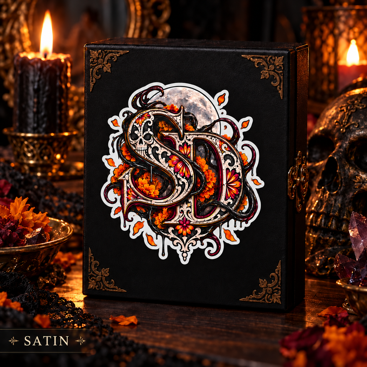 Satin Día de los Muertos SD decal displayed on a black book amid candles and marigolds.