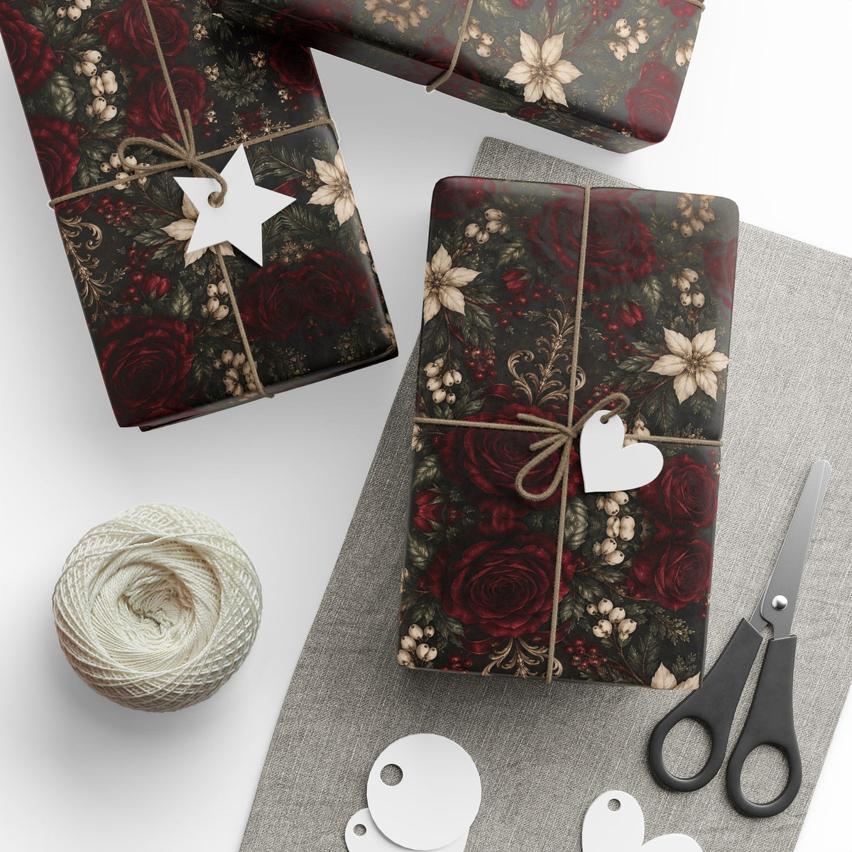 Several gifts wrapped in Burgundy Floral Pattern paper with twine and tags, arranged beside scissors and a ball of twine.