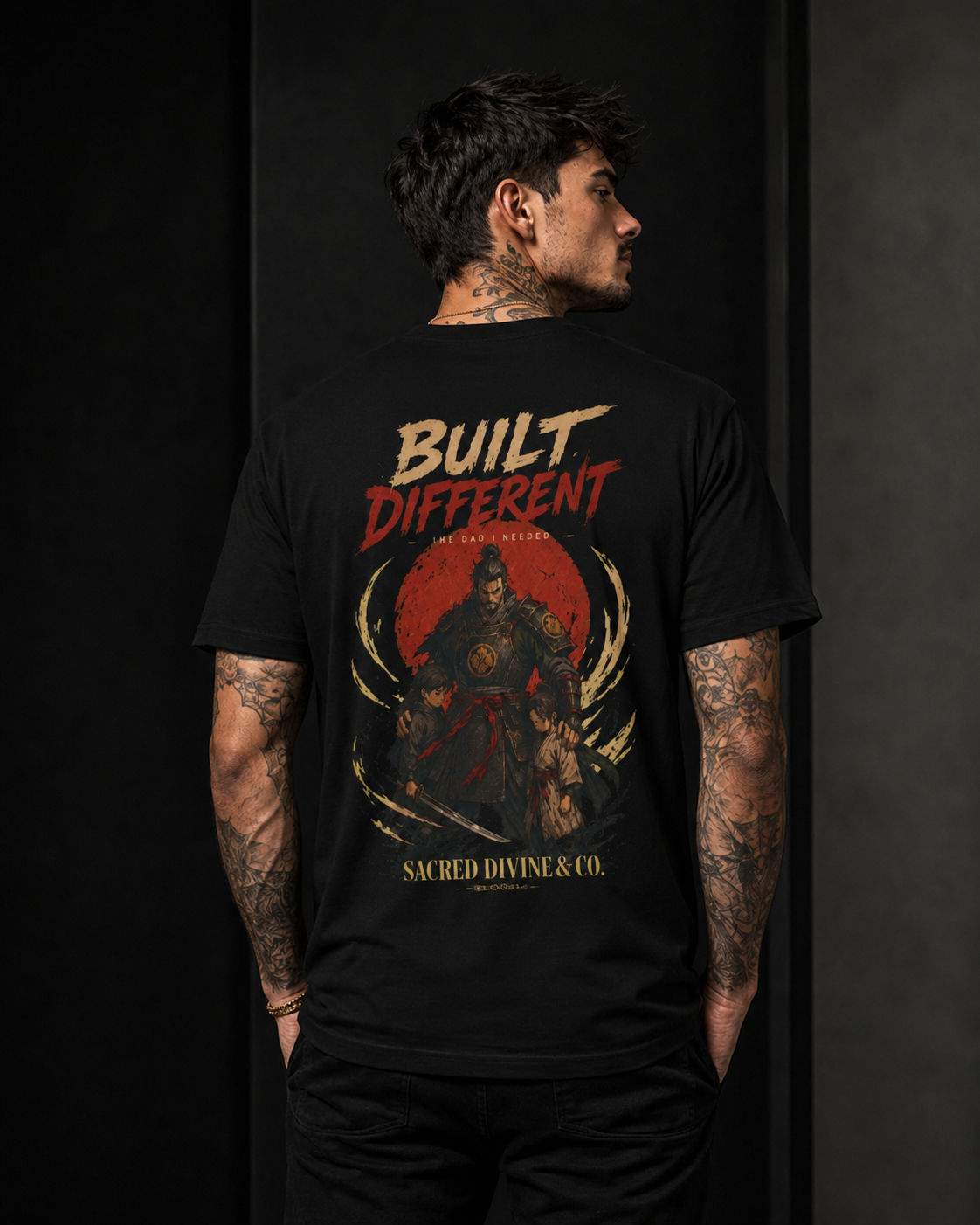 Built Different Tee black back lifestyle — model wearing tee with Built Different The Dad I Needed warrior crest full back graphic and Sacred Divine & Co. wordmark