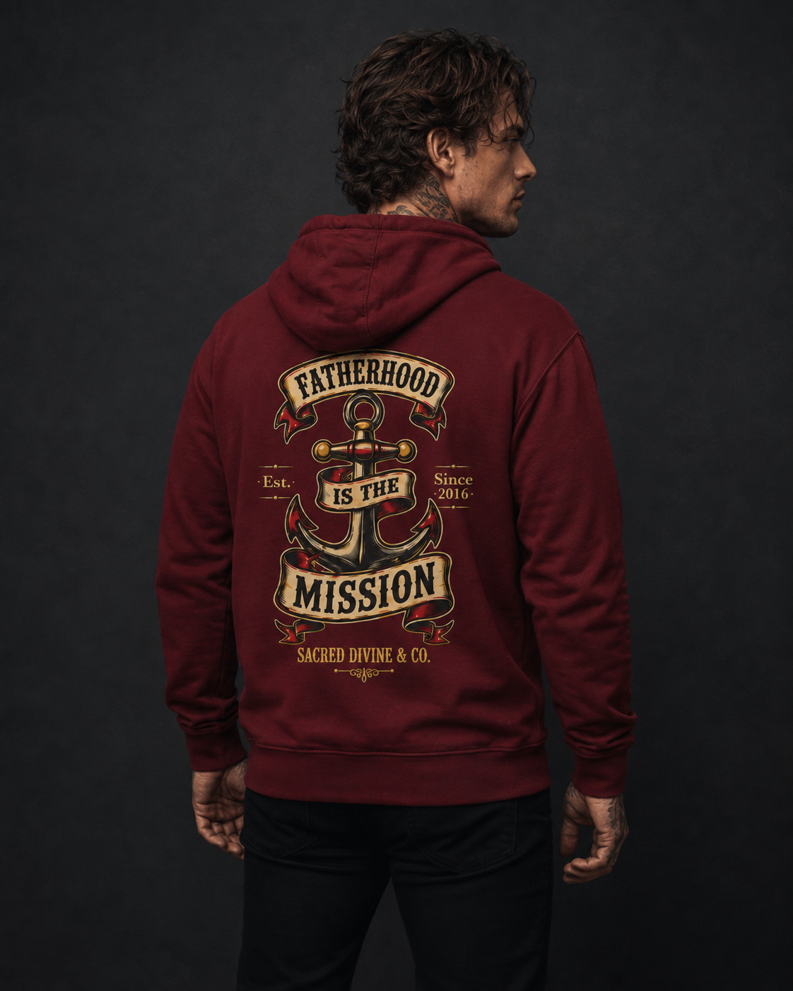 Fatherhood Anchor Hoodie burgundy back lifestyle — model wearing hoodie with Fatherhood Is the Mission vintage anchor banner full back graphic and Sacred Divine & Co. wordmark